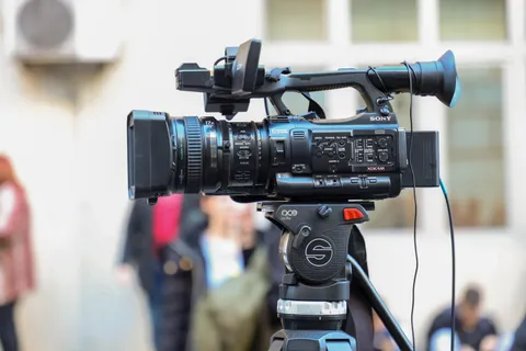 Nahaufnahme einer Sony-Videokamera auf einem Stativ f&uuml;r Au&szlig;enaufnahmen.
