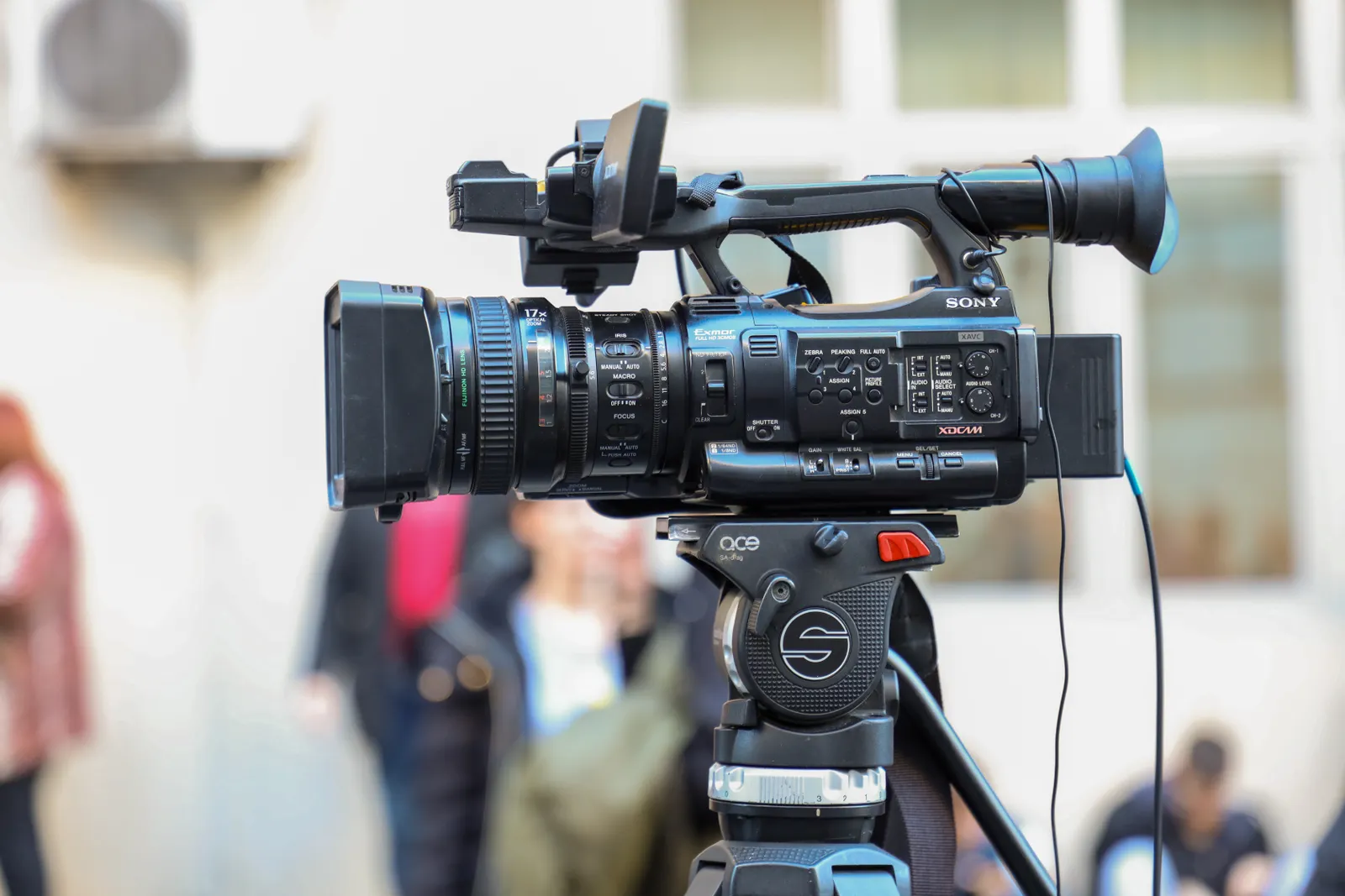 Close-up of a Sony video camera mounted on a tripod for outdoor filming.