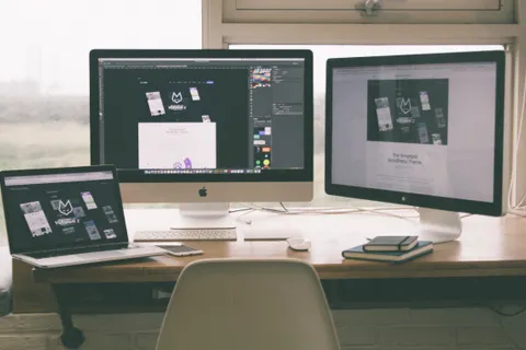 Stilvoller, effizienter Arbeitsplatz mit mehreren Monitoren, Laptop und Smartphone, auf denen ein Webdesign-Projekt zu sehen ist.