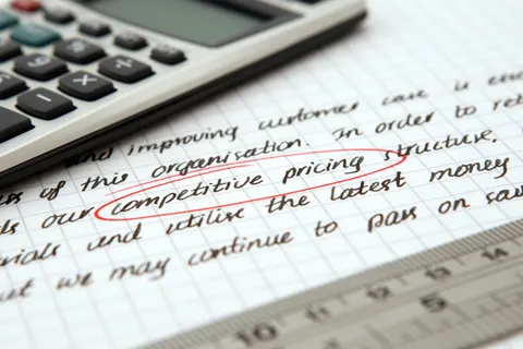Nahaufnahme handschriftlicher Gesch&auml;ftsnotizen zur Preisstrategie, daneben ein Taschenrechner.