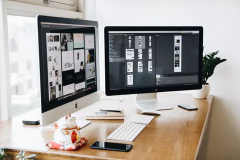 Ein gut organisierter Design-Arbeitsplatz mit zwei Monitoren, auf denen Designsoftware zu sehen ist.