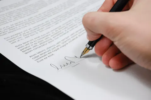 Nahaufnahme einer Hand, die mit einem F&uuml;llfederhalter ein rechtliches Dokument unterschreibt, als Symbol f&uuml;r Unterschrift und Vereinbarung.