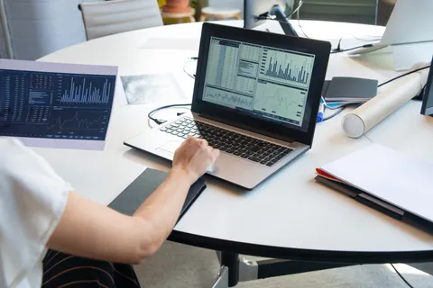 Gesch&auml;ftsperson wertet in einem modernen B&uuml;ro Finanzdiagramme auf einem Laptop aus.