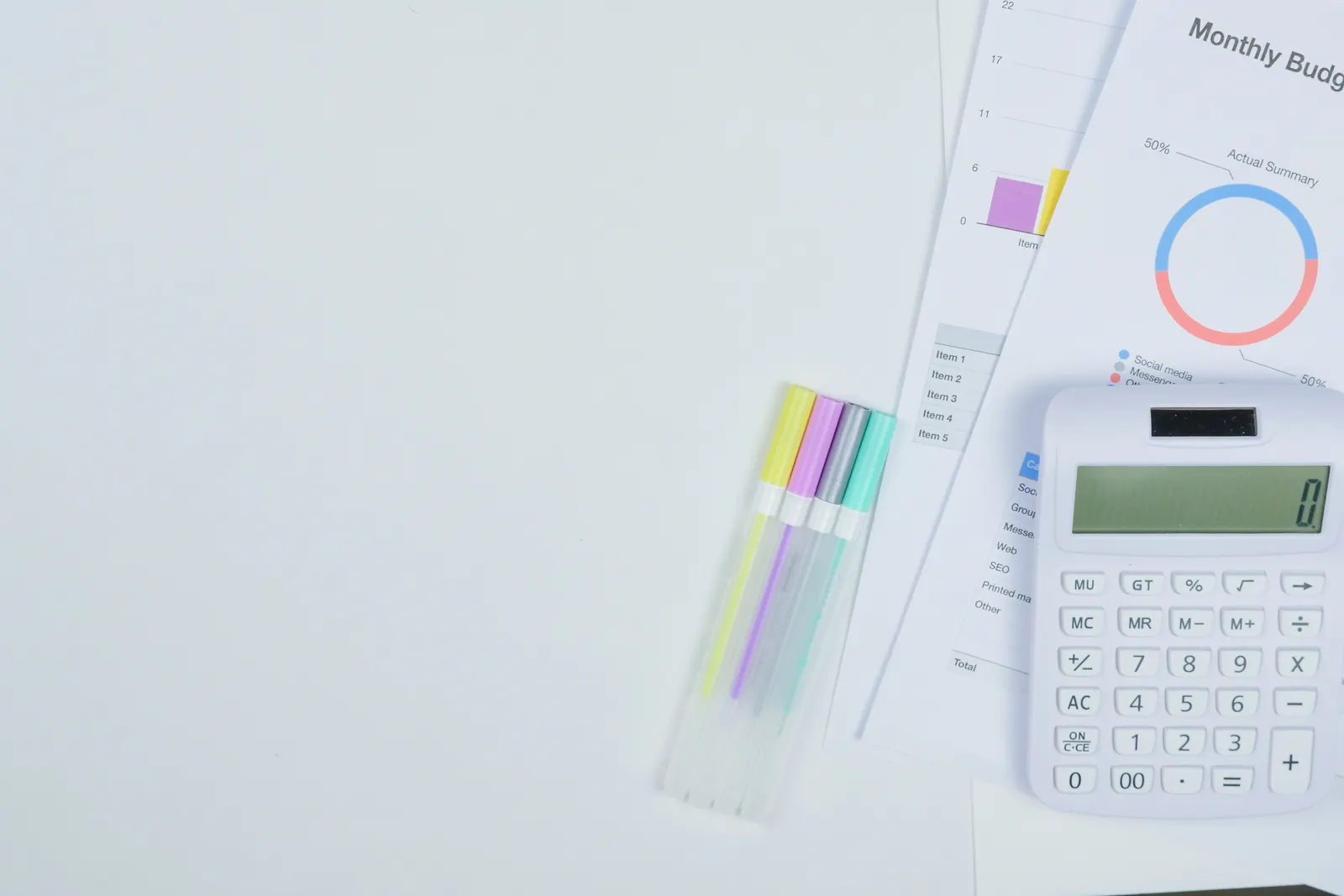 Minimalist office desk with a calculator, budget planning documents, and colorful pens.