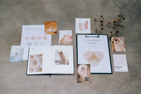 Flatlay mit Branding-Elementen, Farbpaletten und Unterlagen zur strategischen Planung auf einer Betonoberfl&auml;che.