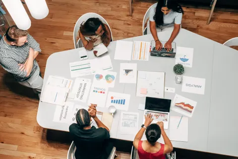 Eine vielf&auml;ltige Gruppe arbeitet in einem B&uuml;ro mit Diagrammen und Laptops an Marketingstrategien.