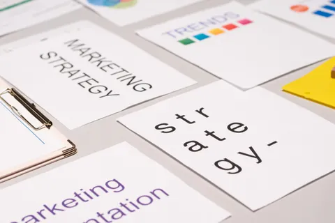 Draufsicht auf Unterlagen und Diagramme zur Marketingstrategie auf einem Schreibtisch, als Sinnbild f&uuml;r Gesch&auml;ftsplanung.